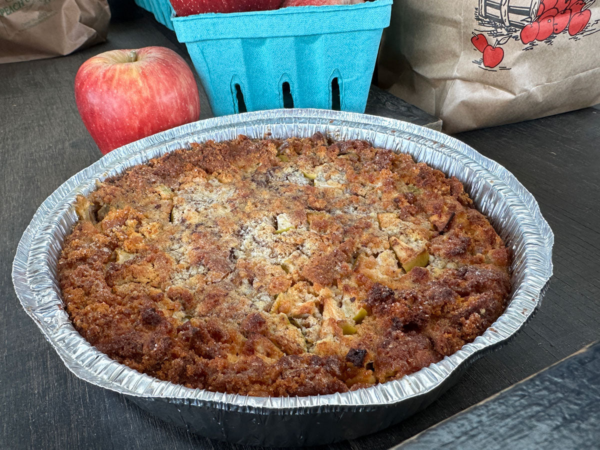 Apple cider donut bread pudding on a wooden surface with an apple behind it