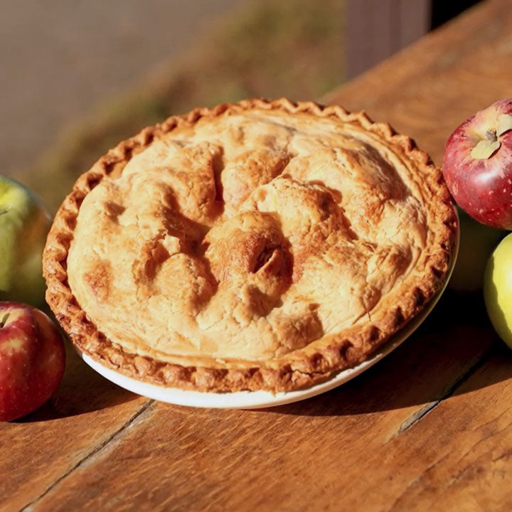 Apple pie on wooden table with fresh orchard apples